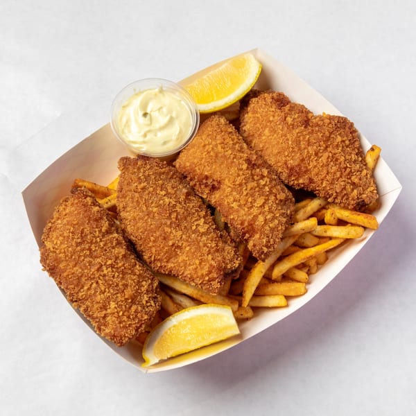 Crispy fried fish and chips in a paper tray, with tartar sauce and lemon wedges.